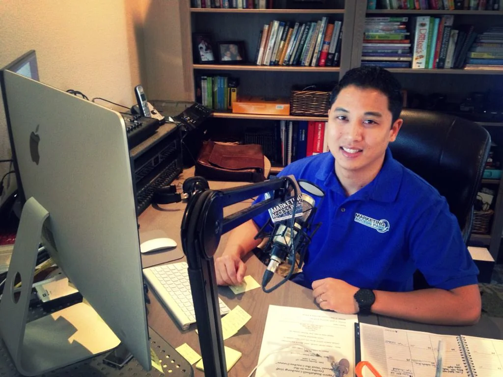Anthony Tran at his Marketing Access Pass desk setup, branded polo and podcast microphone